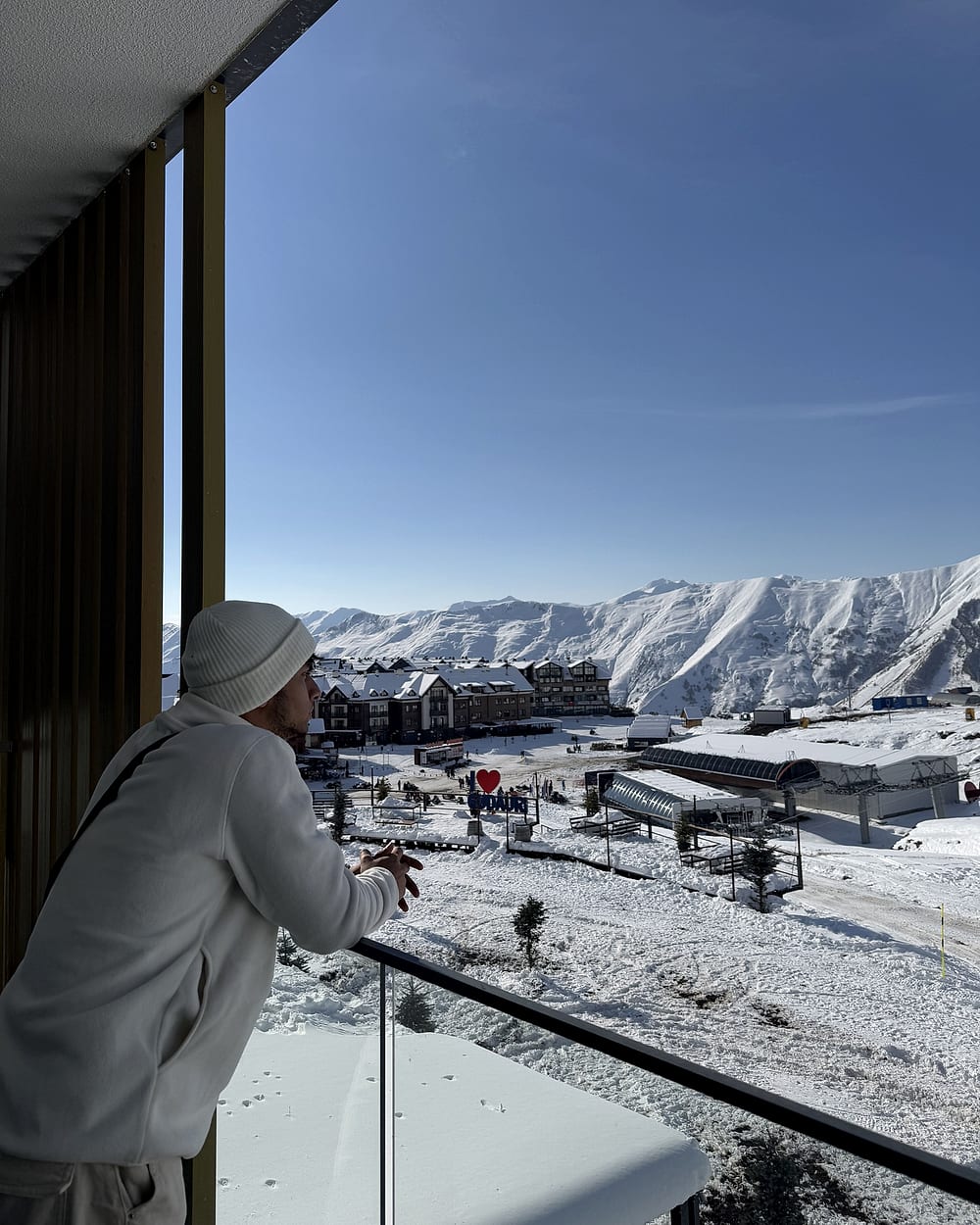 Nasif on a balcony in Gudauri, Georgia, looking out at the snowy mountains